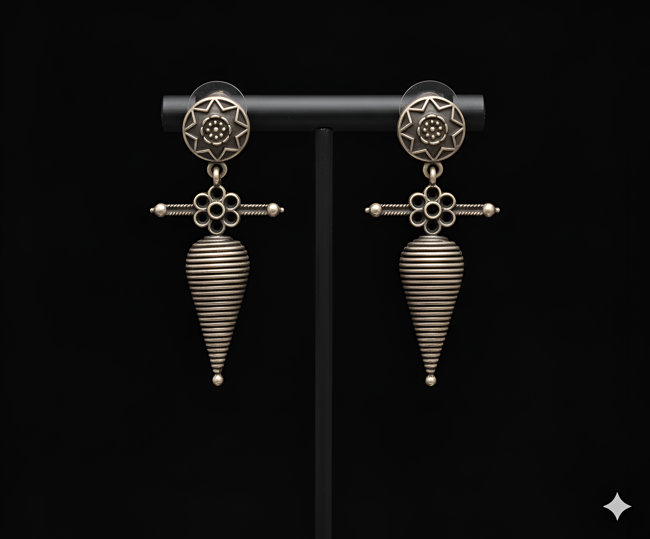 Shell inspired tribal drop earrings displayed on black stand

