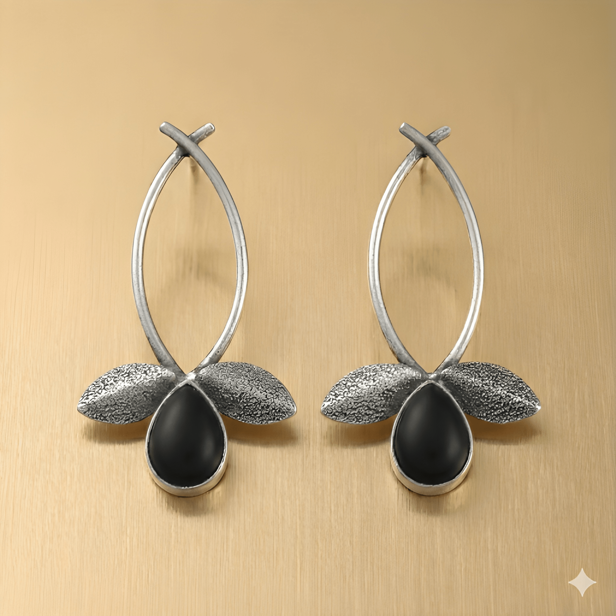 Leaf drop earrings with teardrop stone on golden background

