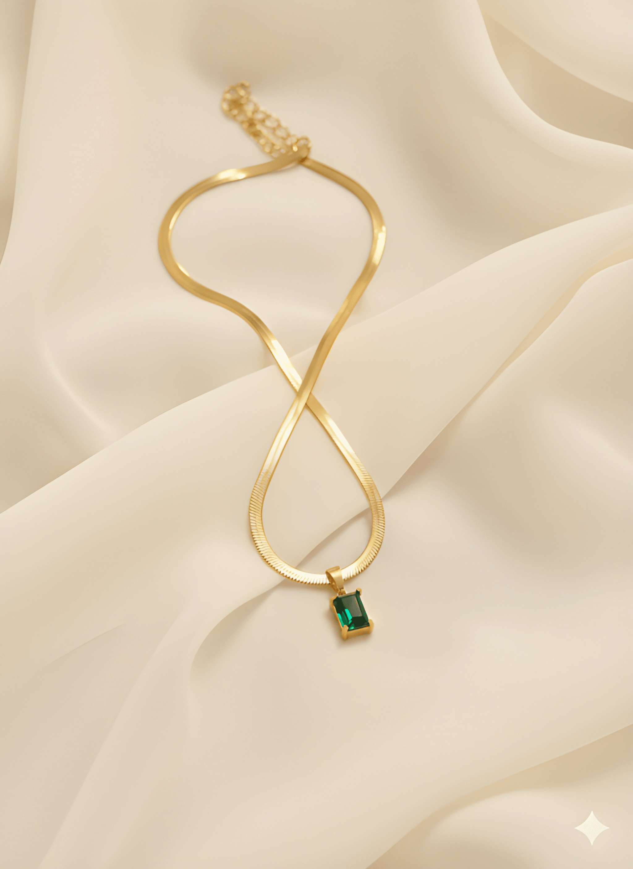 Gold rectangle pendant necklace with green stone on ivory fabric