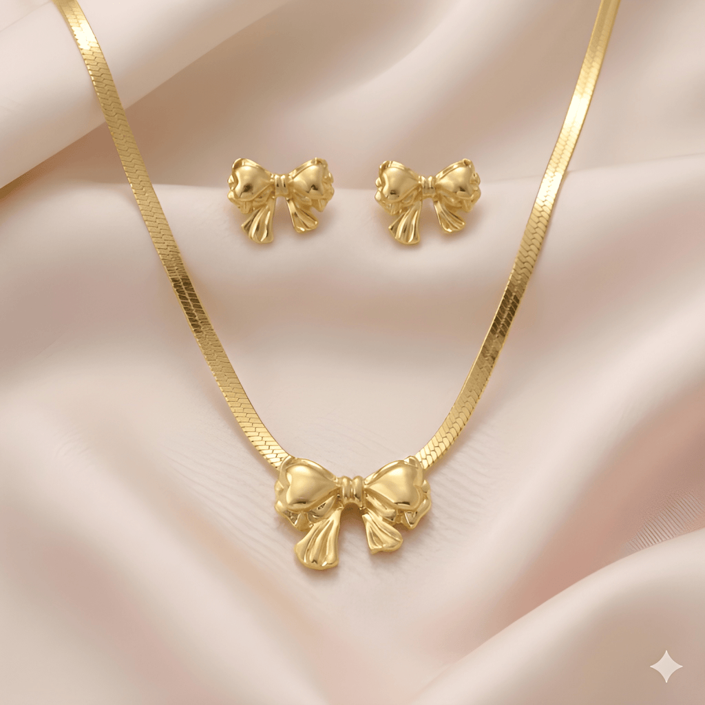 Gold bow pendant necklace with matching bow stud earrings on soft ivory silk background | Kayahh Jewels