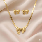 Gold bow pendant necklace with matching bow stud earrings on soft ivory silk background | Kayahh Jewels